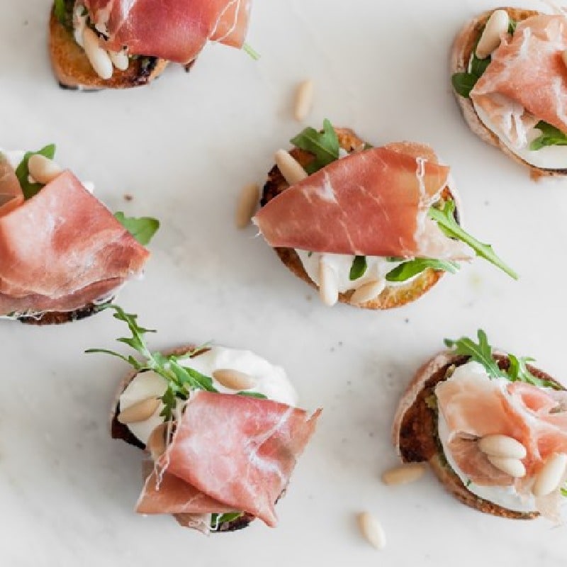 Crostini with rocket, buffalo stracciatella, Parma Ham and pine nuts